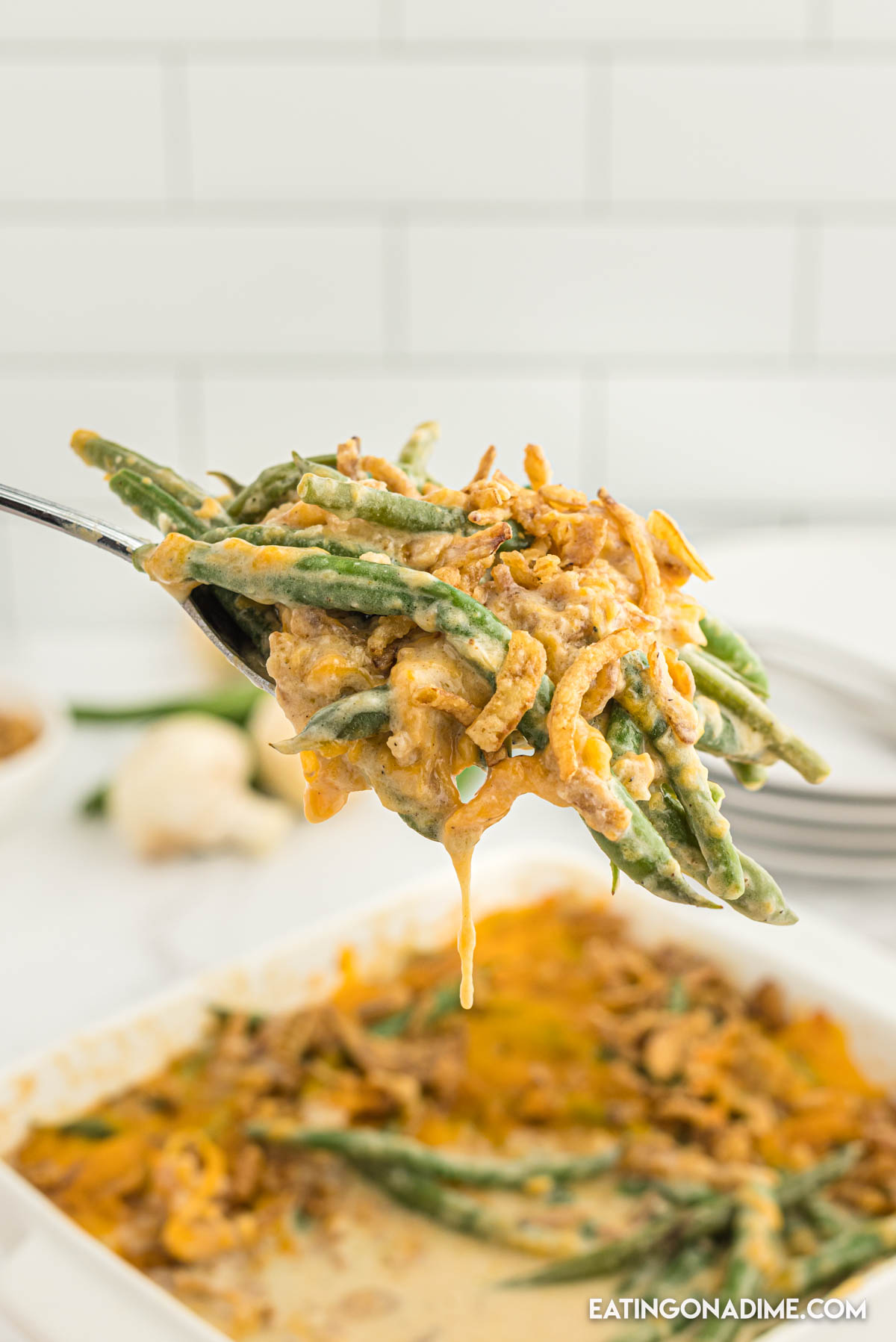 A serving of cheesy green bean casserole on a spoon