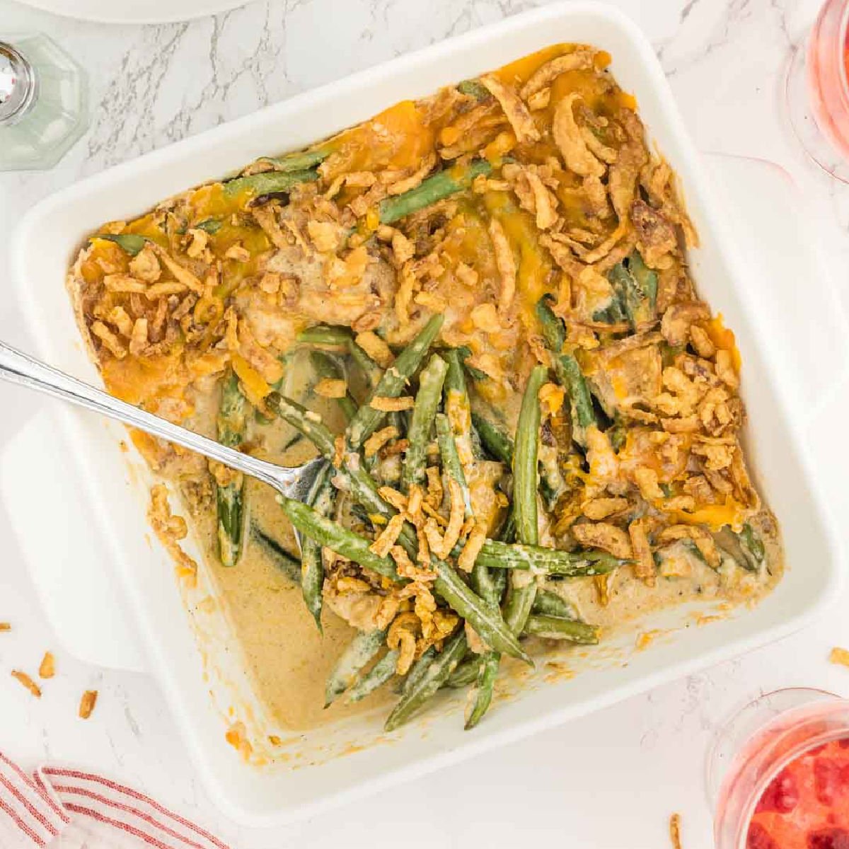 Cheesy green bean casserole in a baking dish with a spoon