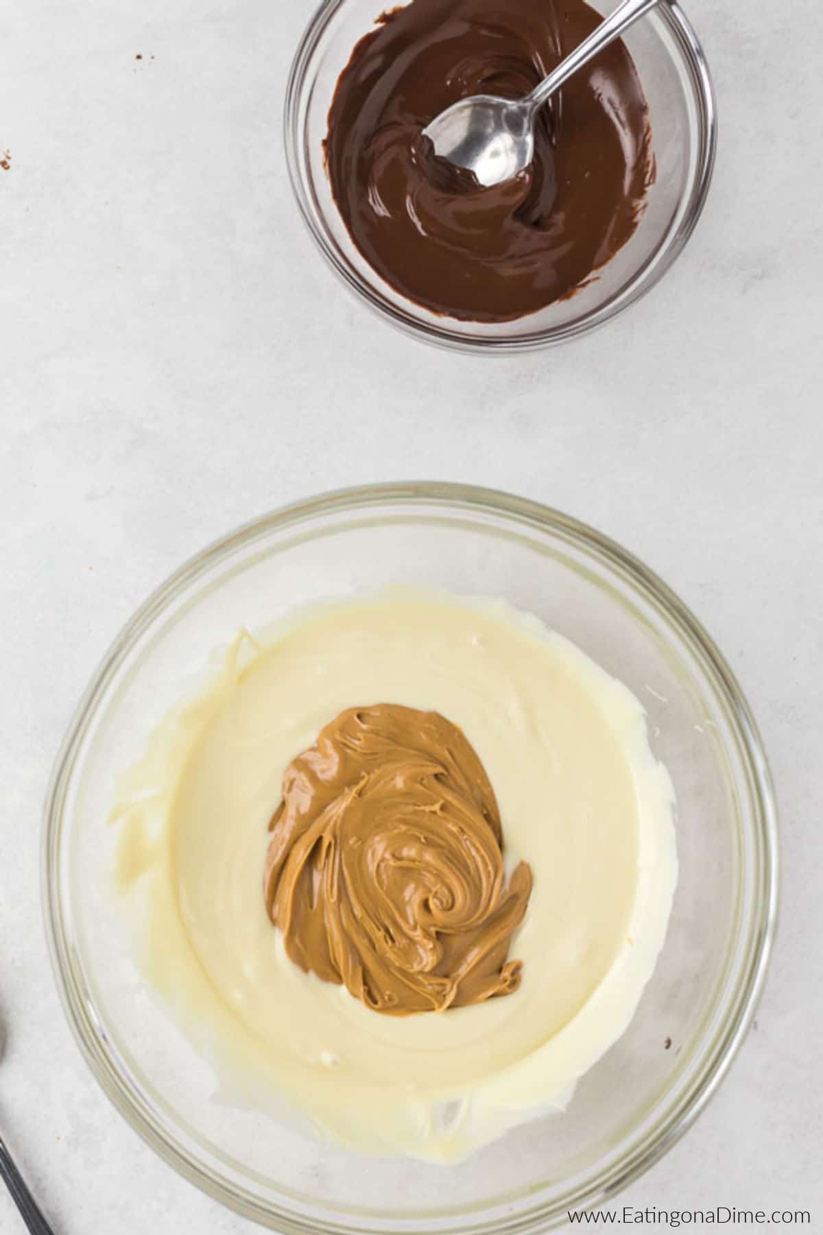 Peanut butter added to the melted vanilla chips in a bowl with the melted chocolate nearby.