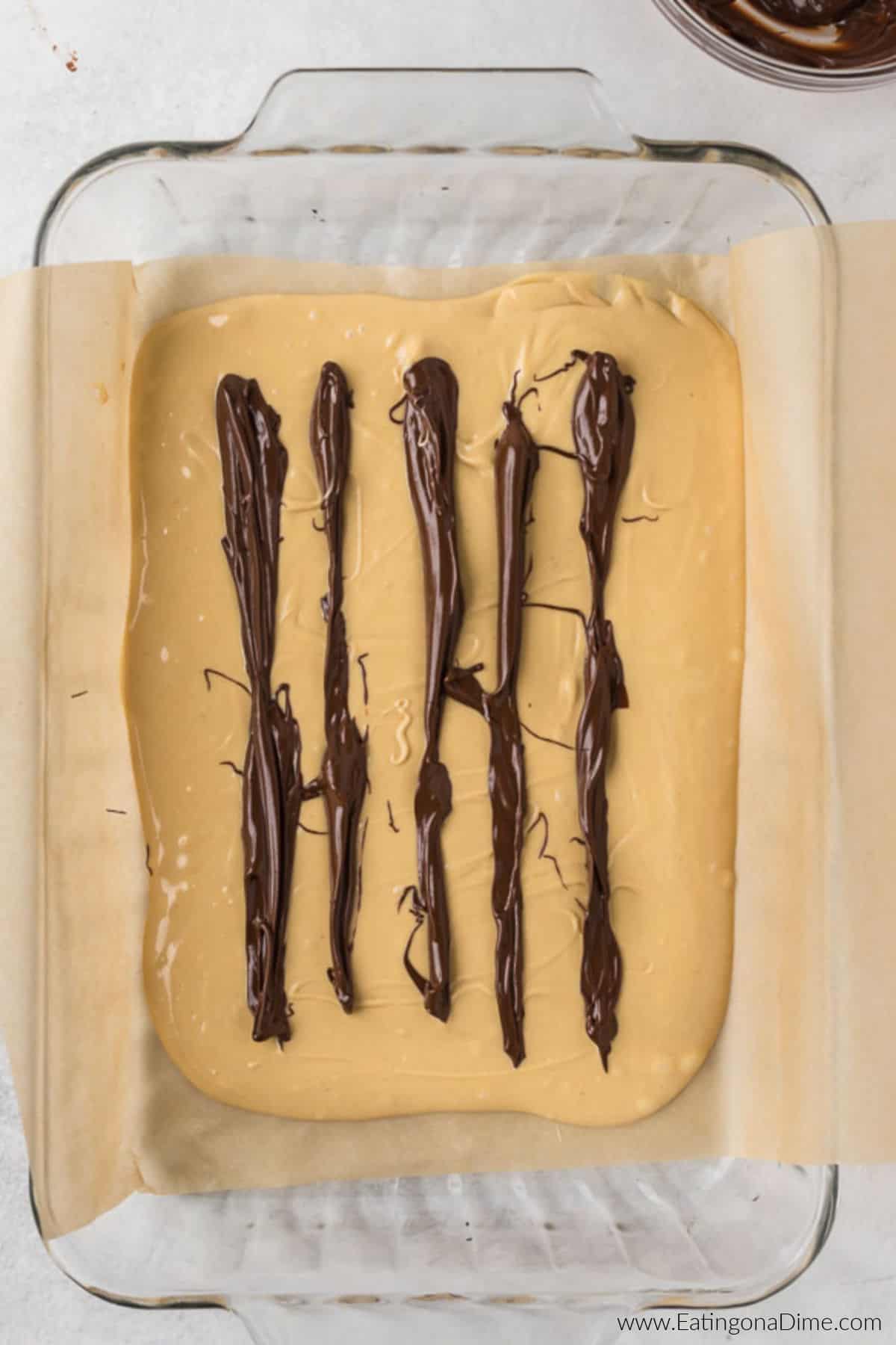 Melted chocolate poured into the peanut butter mixture in the baking dish.