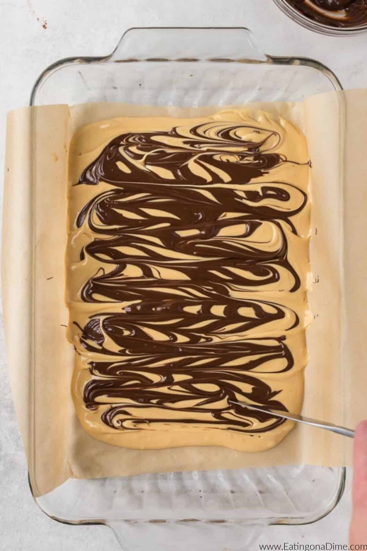 Melted chocolate mixture swirled into the peanut butter mixture in a baking dish.
