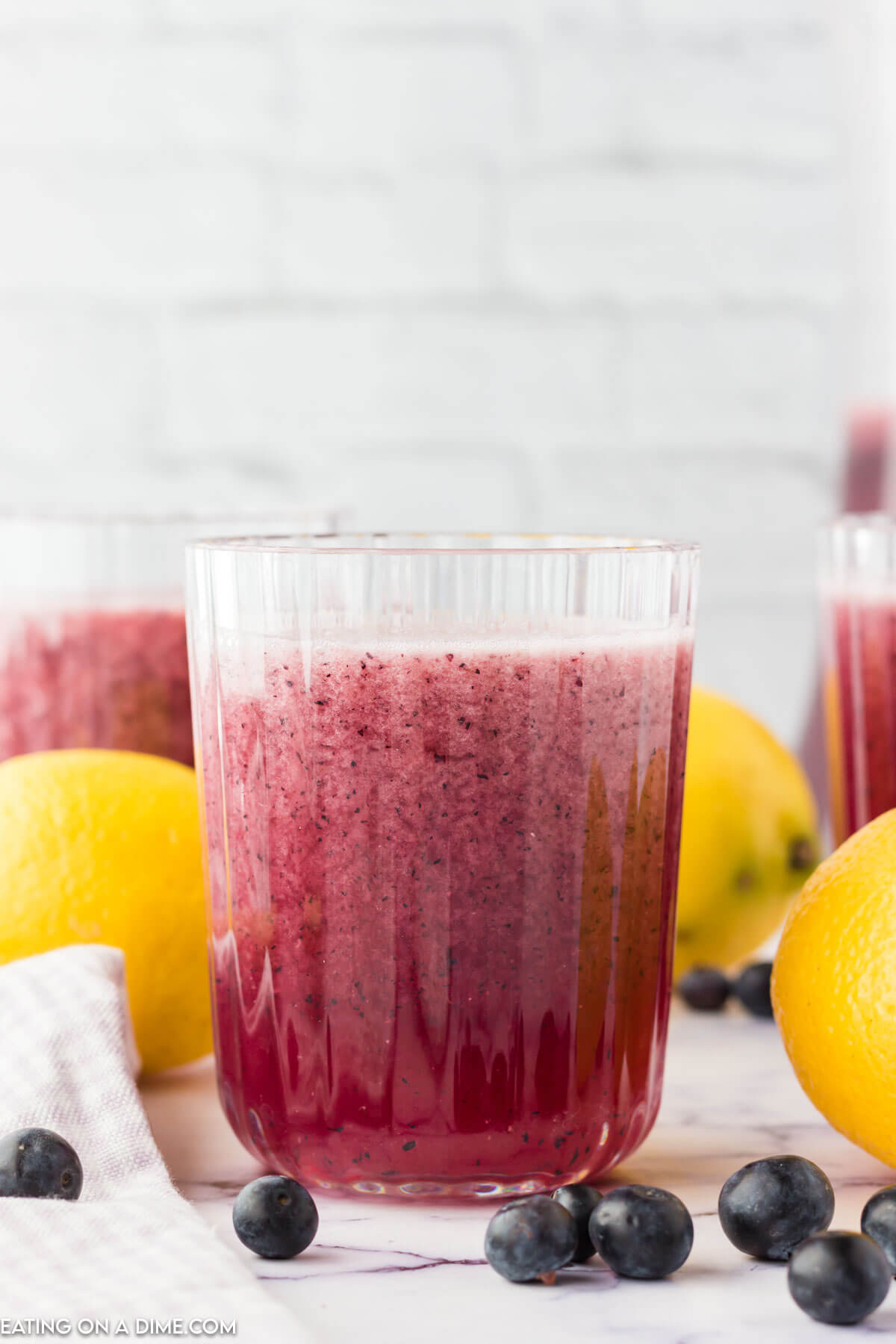 Blueberry Lemonade in a glass with fresh lemons on the side