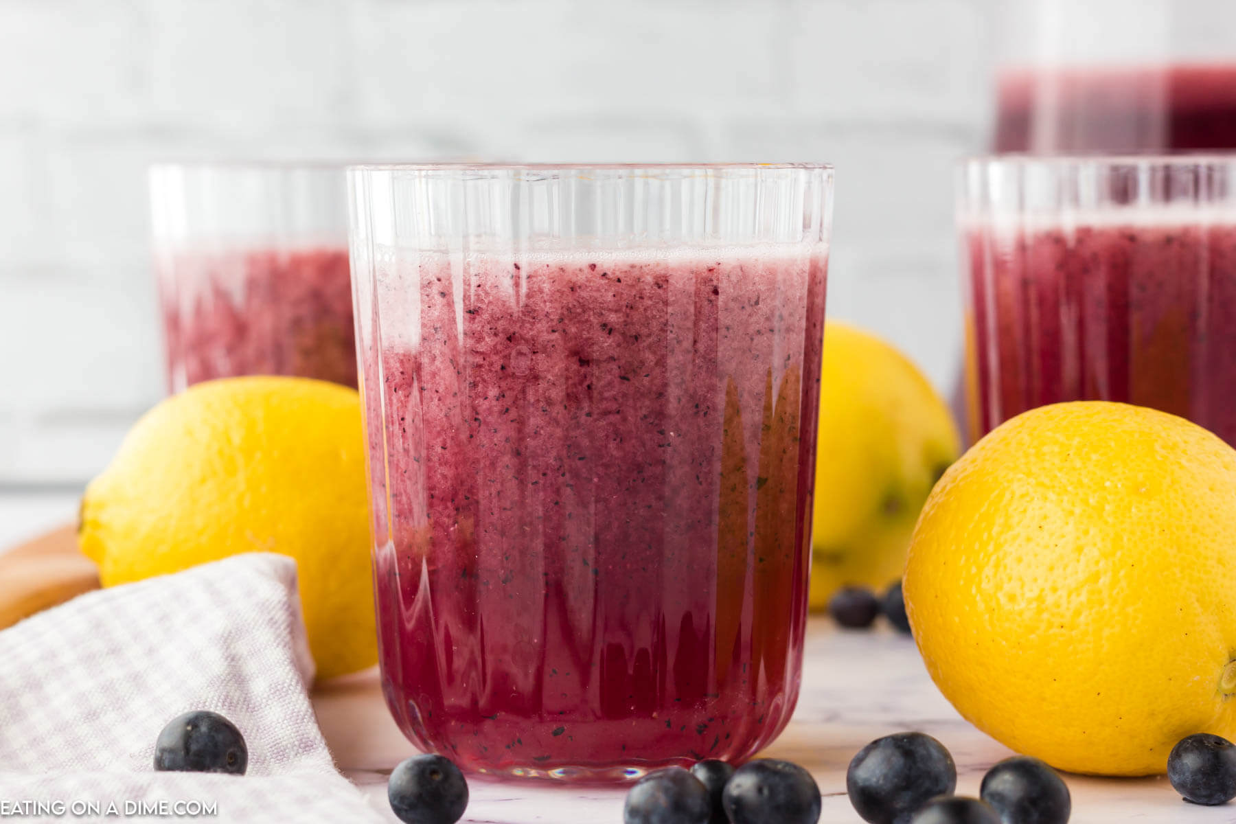 Blueberry Lemonade in a glass with fresh lemons on the side