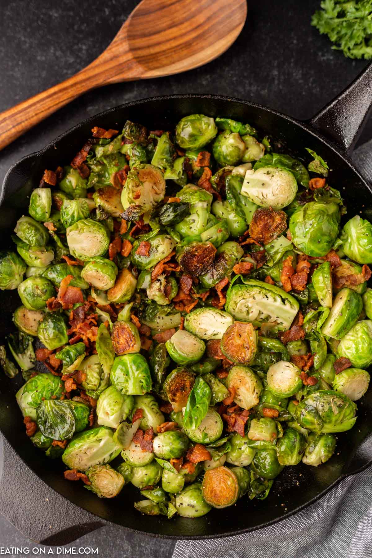 Close up image of bacon brussel sprouts on a black plate