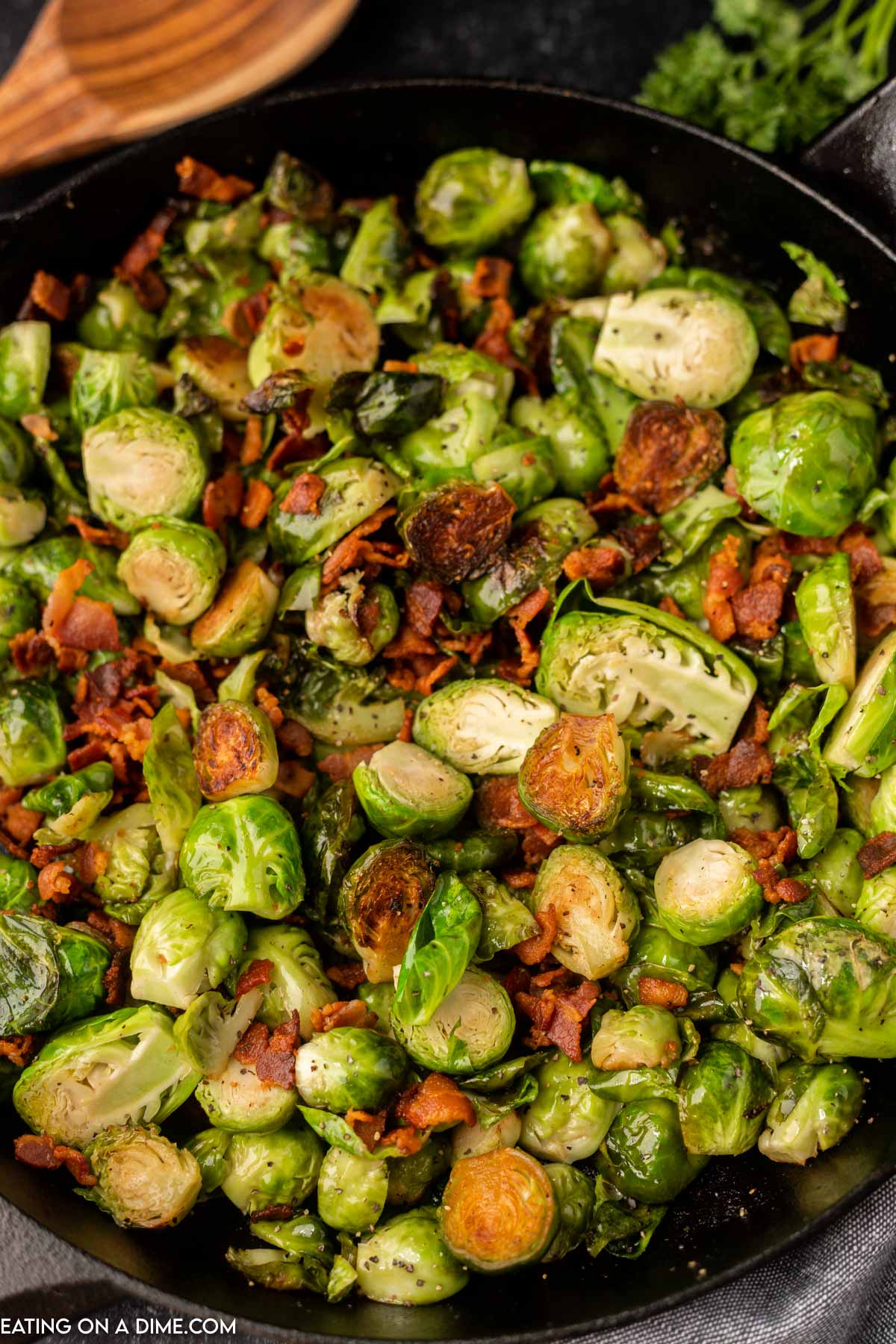 Close up image of bacon brussel sprouts on a black plate