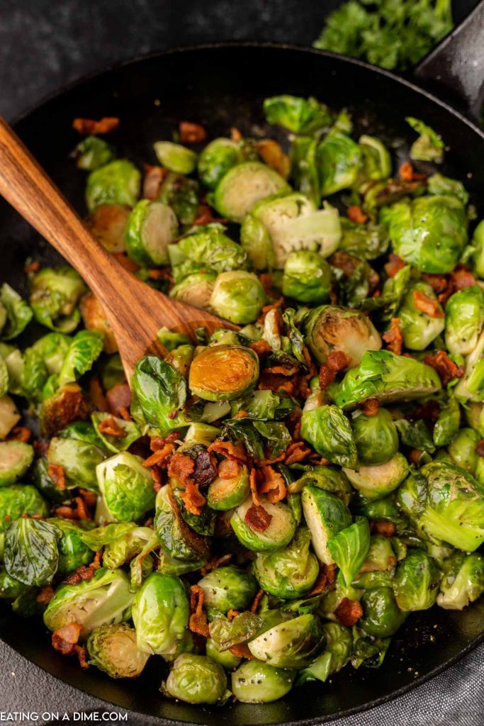 Close up image of bacon brussel sprouts with a wooden spoon
