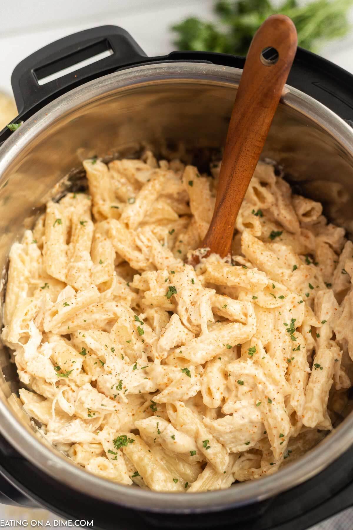 Creamy Cajun Chicken Pasta in the Instant Pot with a wooden spoon