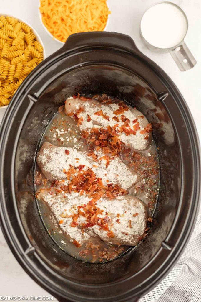 chicken bacon and other ingredients uncooked in the crock pot