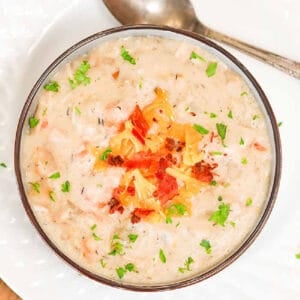 Potato soup with chicken in a bowl topped with red bell peppers and cheese.