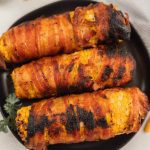 Three corn on the cob wrapped in bacon.