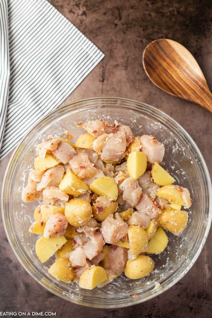 Chicken and potatoes in bowl with seasoning. 