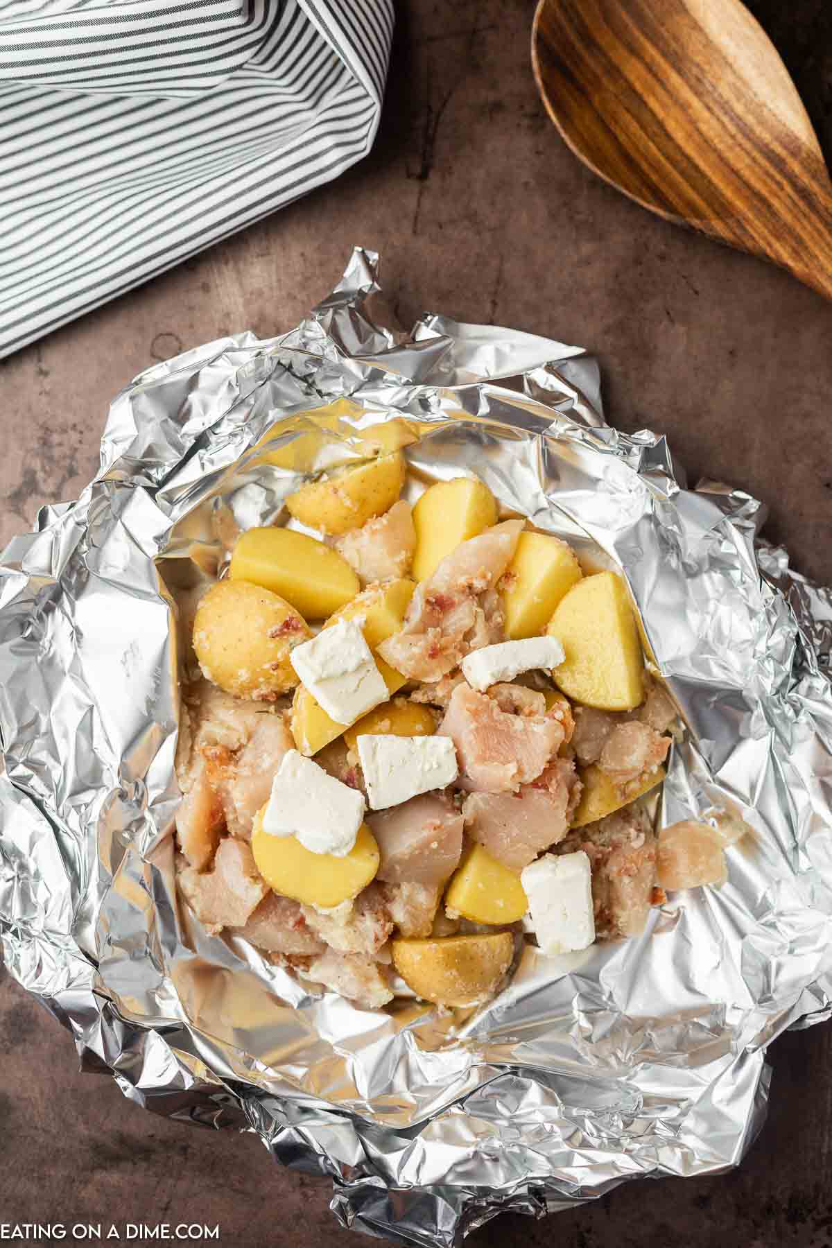 Chicken and potato mixture topped on a piece of foil with cubed cream cheese
