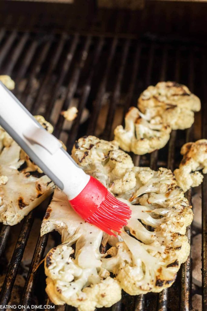 Cauliflower steaks being basted on the grill. 