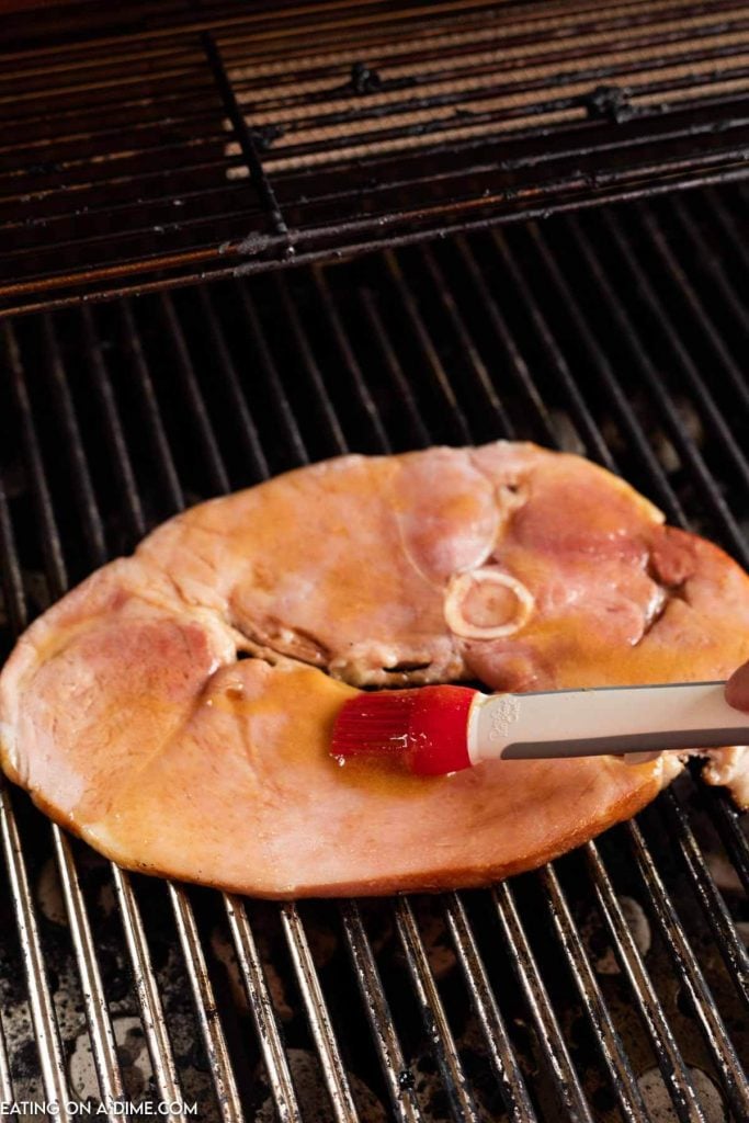 Ham steak on the grill being basted. 