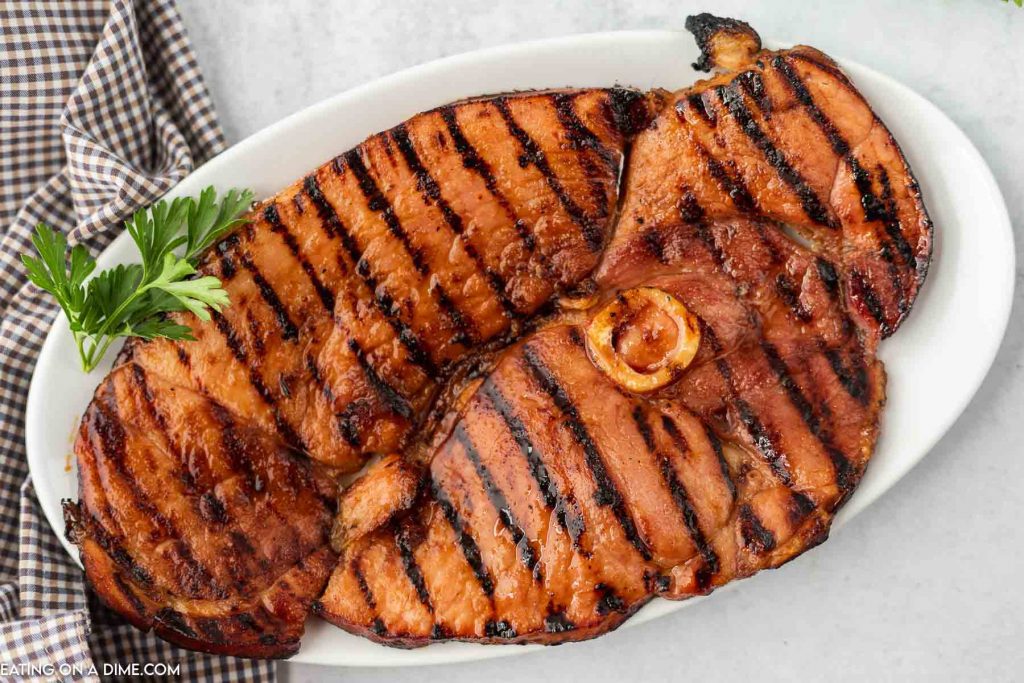 Grilled ham steak on a white plate.