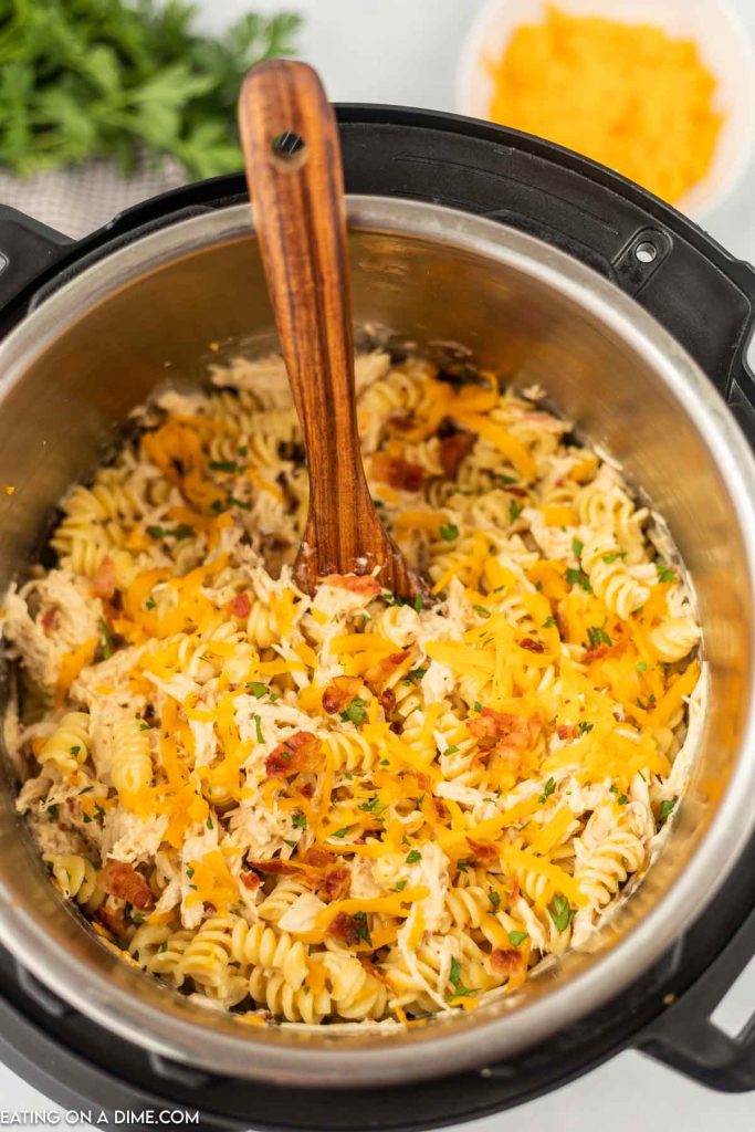 Close up image of bacon ranch pasta in the instant pot with a wooden spoon