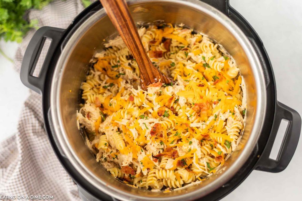 Close up image of bacon ranch pasta in the instant pot with a wooden spoon