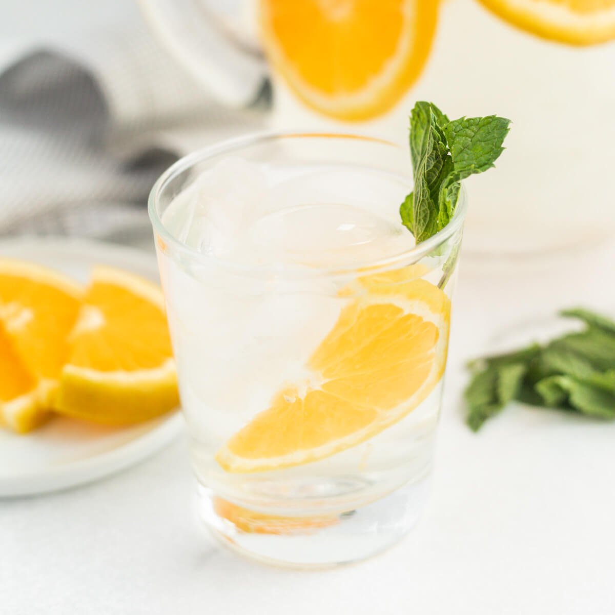 A glass of orange water with a side of mint