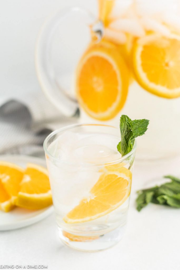 A glass of orange water with a side of mint