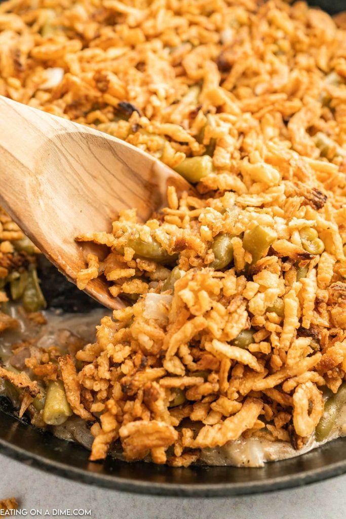 skillet green bean casserole and a serving on a wooden spoon