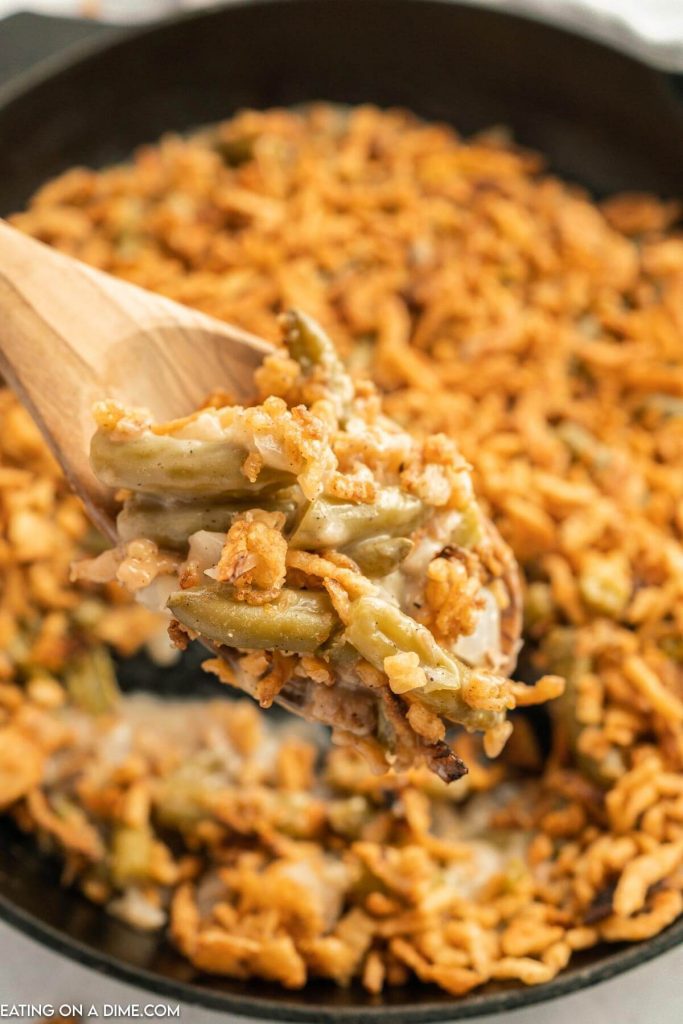 skillet green bean casserole and a serving on a wooden spoon