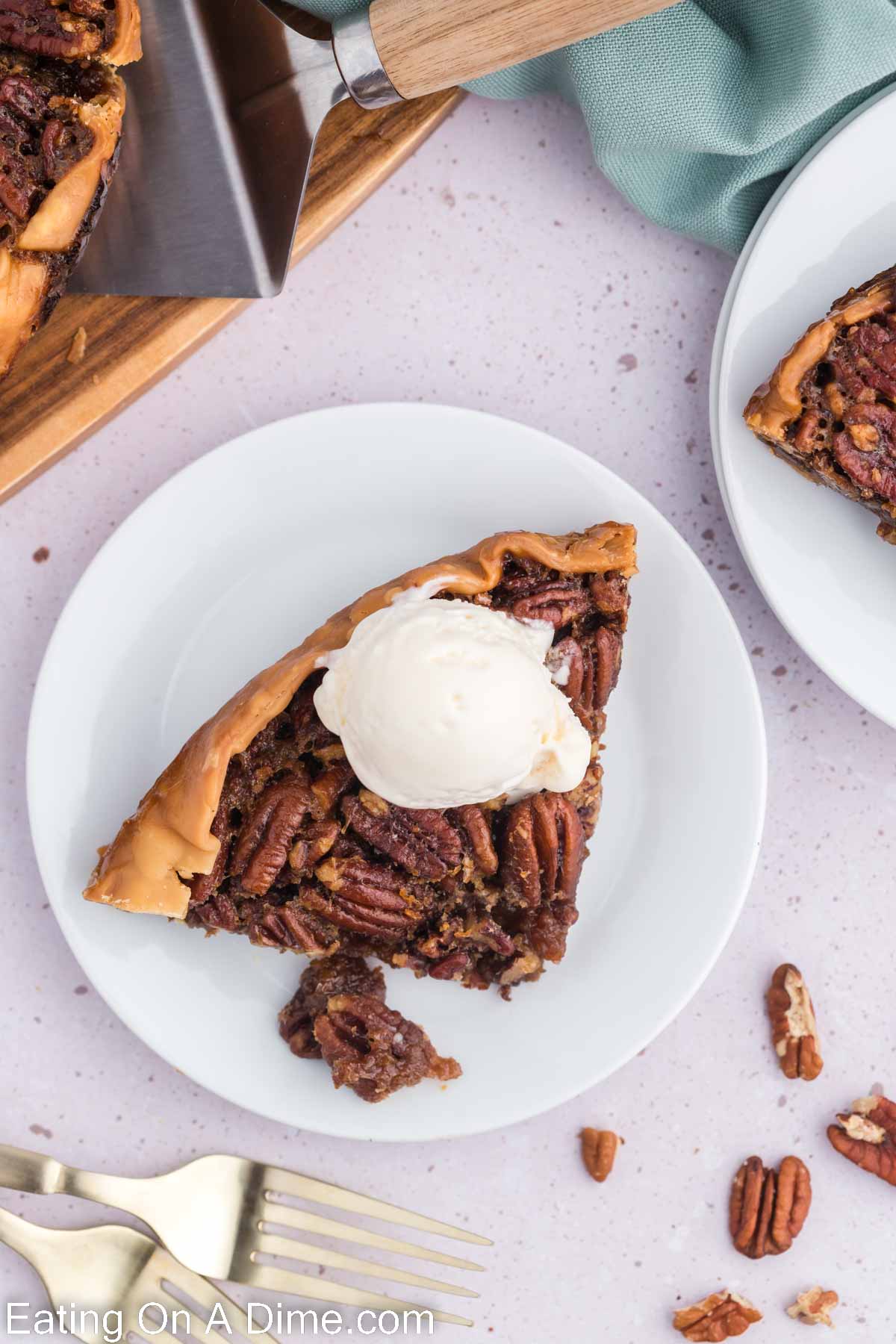 slice of pecan pie on a white plate with a scoop of ice cream
