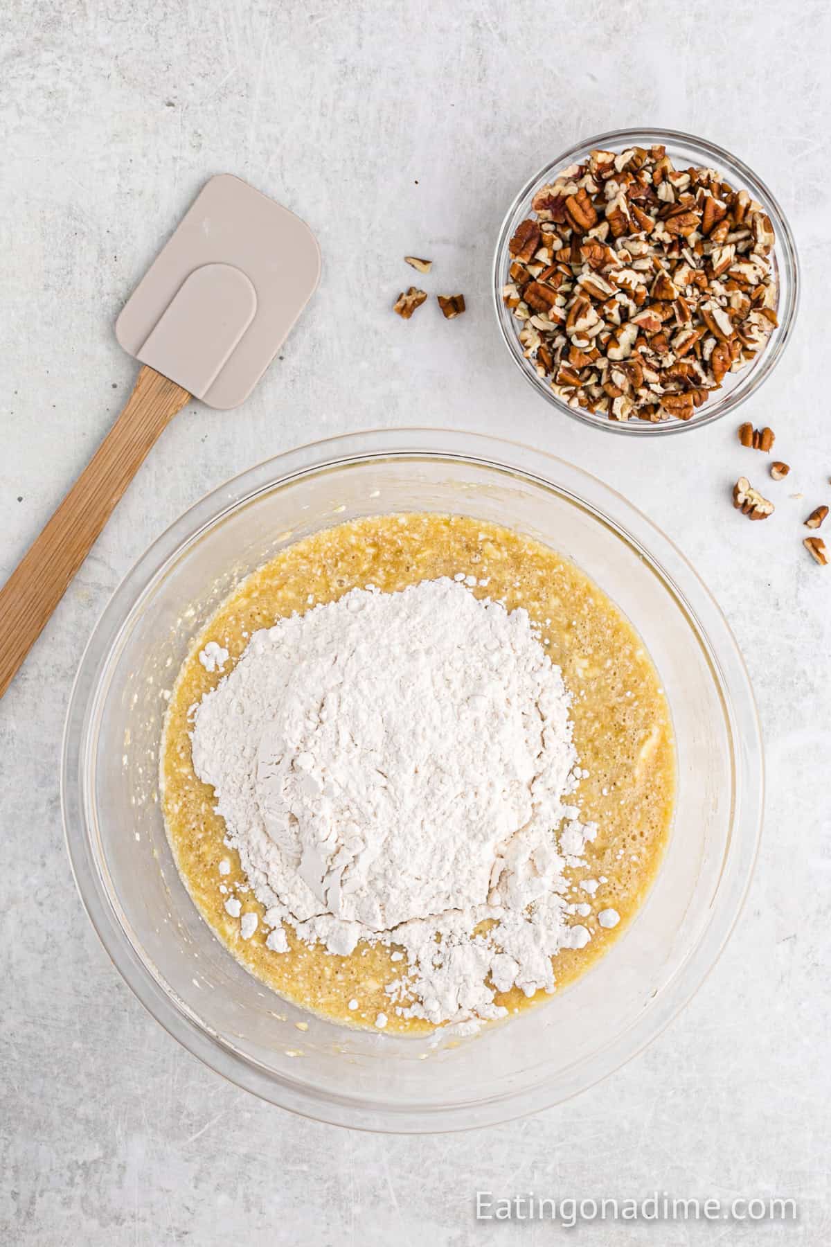 Adding flour to the bowl with the banana mixture.