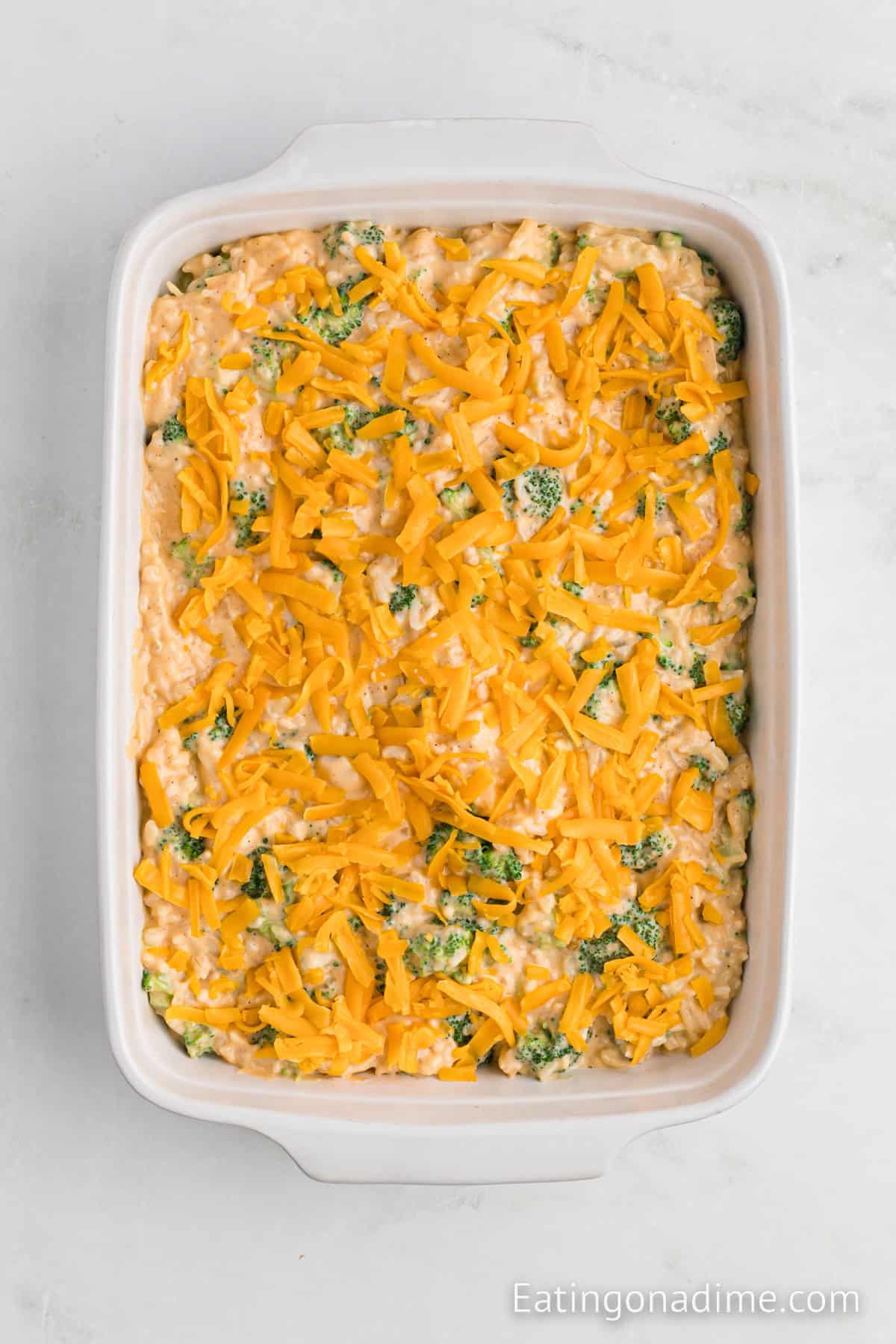 Broccoli and cheese mixture in a baking dish topped with shredded cheese.