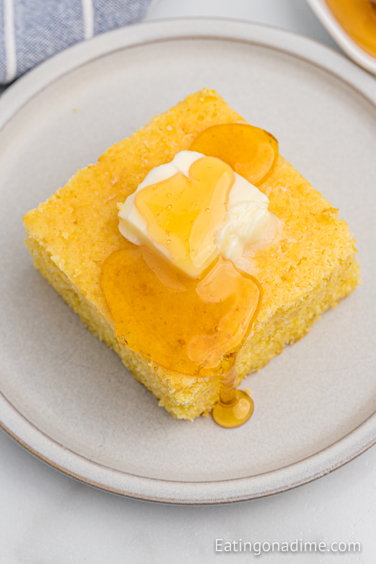 A slice of cornbread on a plate with syrup and butter on top.
