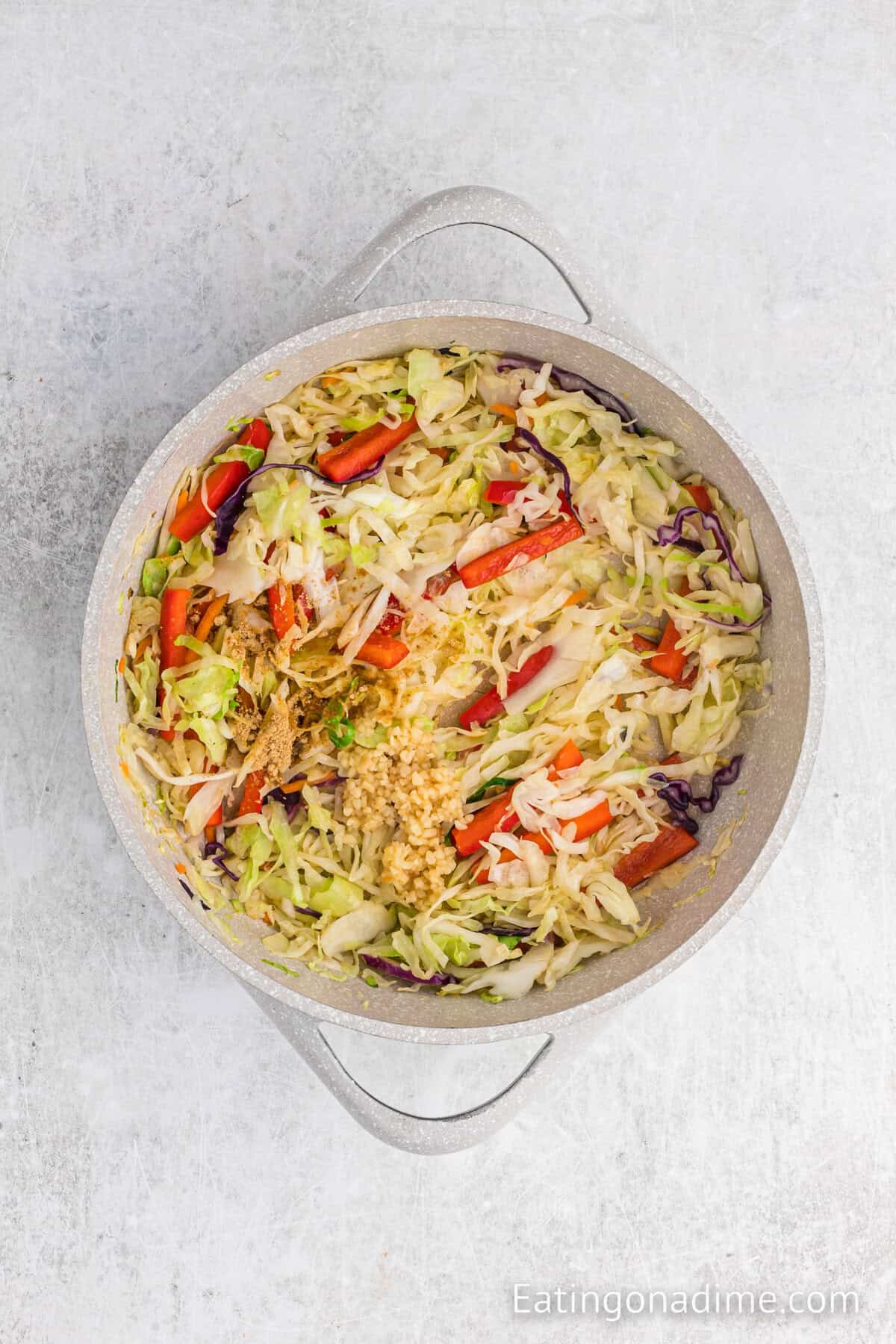 Cooked vegetables topped with minced garlic and ginger in a skillet.