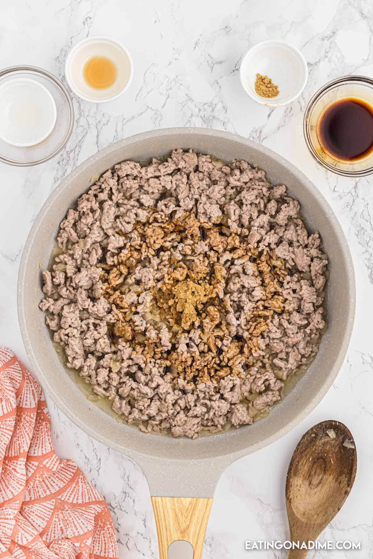 Cooked ground turkey in the skillet topped with the seasoning and sauce 
