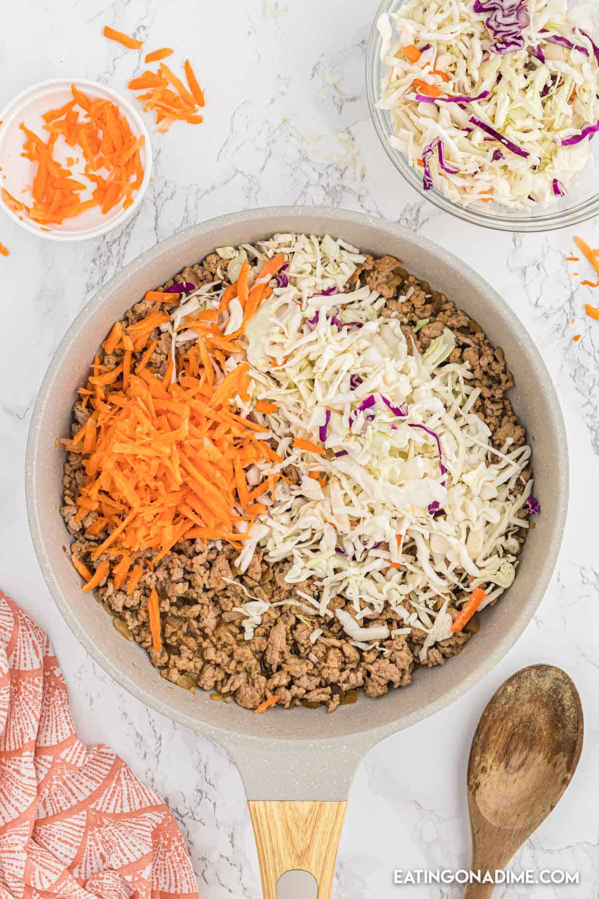 Shredded carrots and coleslaw mix topped the ground turkey in a skillet 