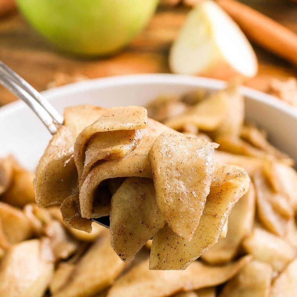 Fried Apples in a white dish with a serving on a spoon