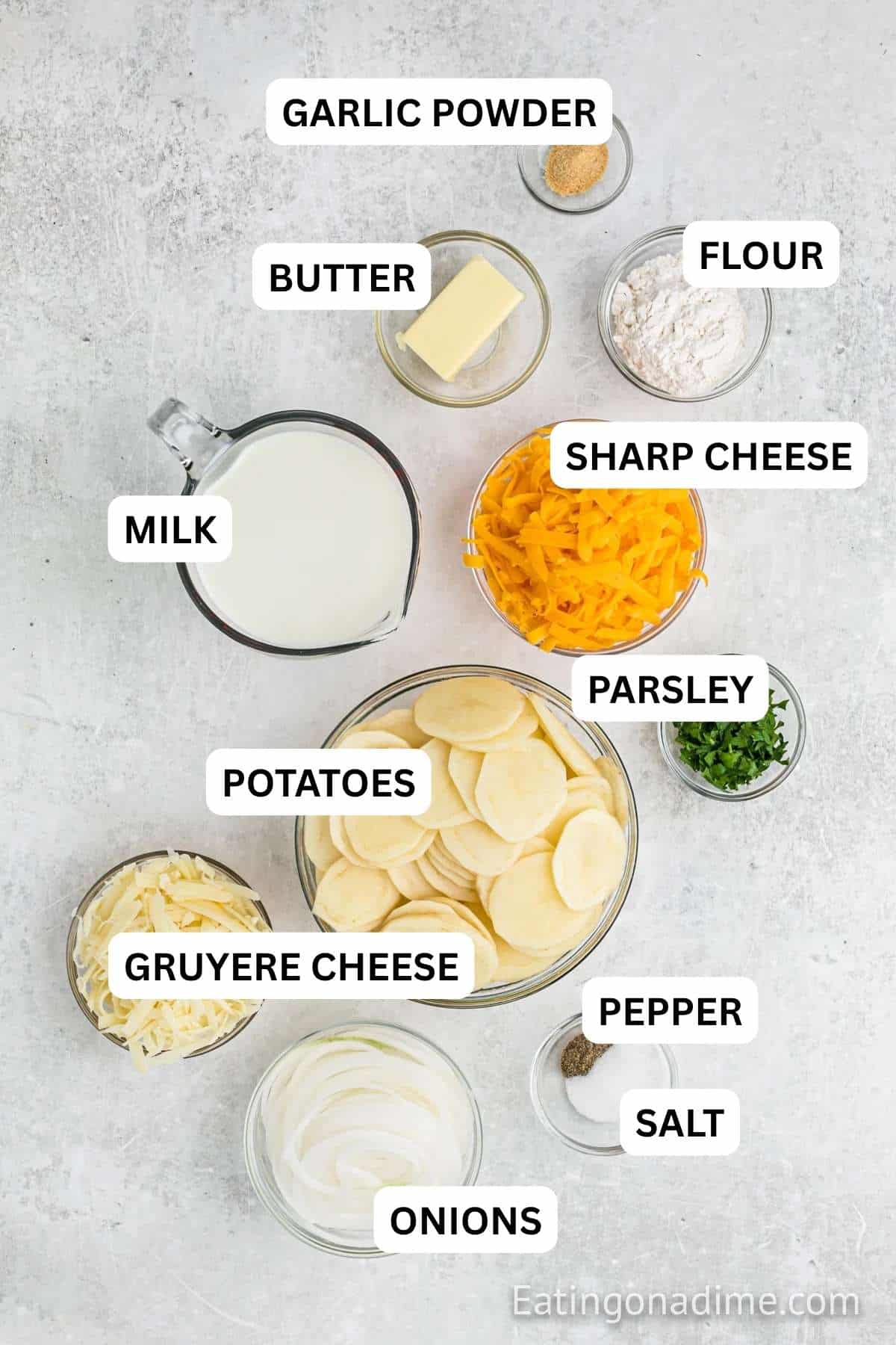 Ingredients needed to make recipe which includes russet potatoes, white onion, butter, flour, garlic powder, milk, cheddar cheese, gruyere cheese, salt and pepper, parsley.