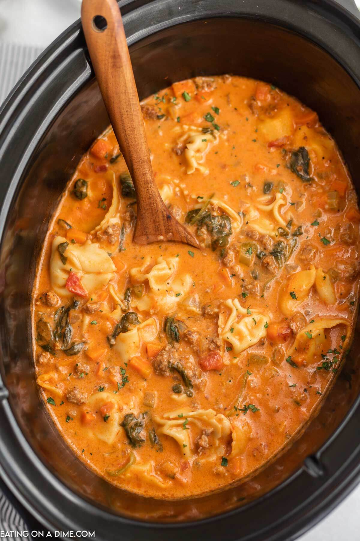 Close up image of creamy sausage tortellini soup in the slow cooker