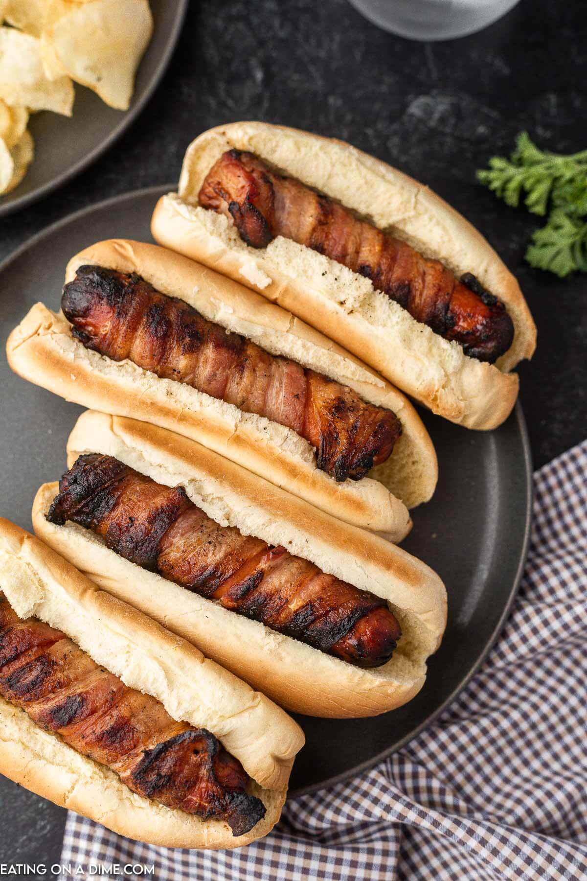 Bacon wrapped hot dogs on a plate. 