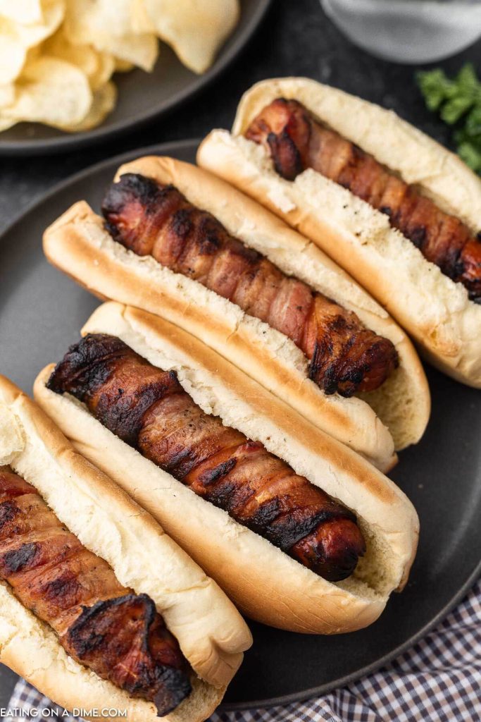 Bacon wrapped hot dogs on a plate. 