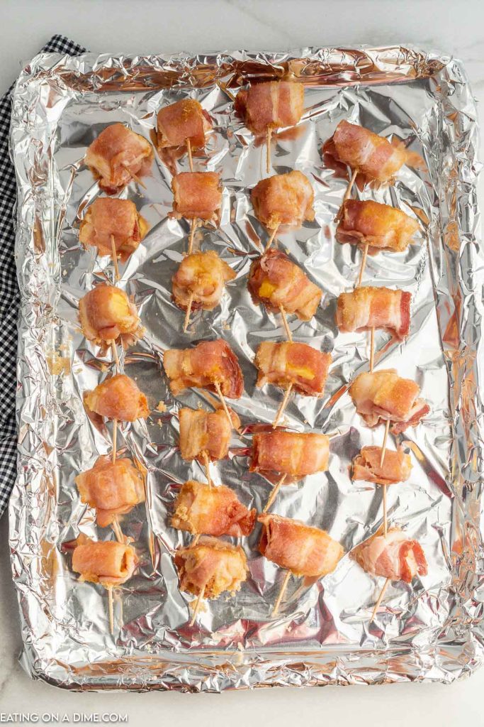 Placing in the bacon wrapped pineapple on baking sheet