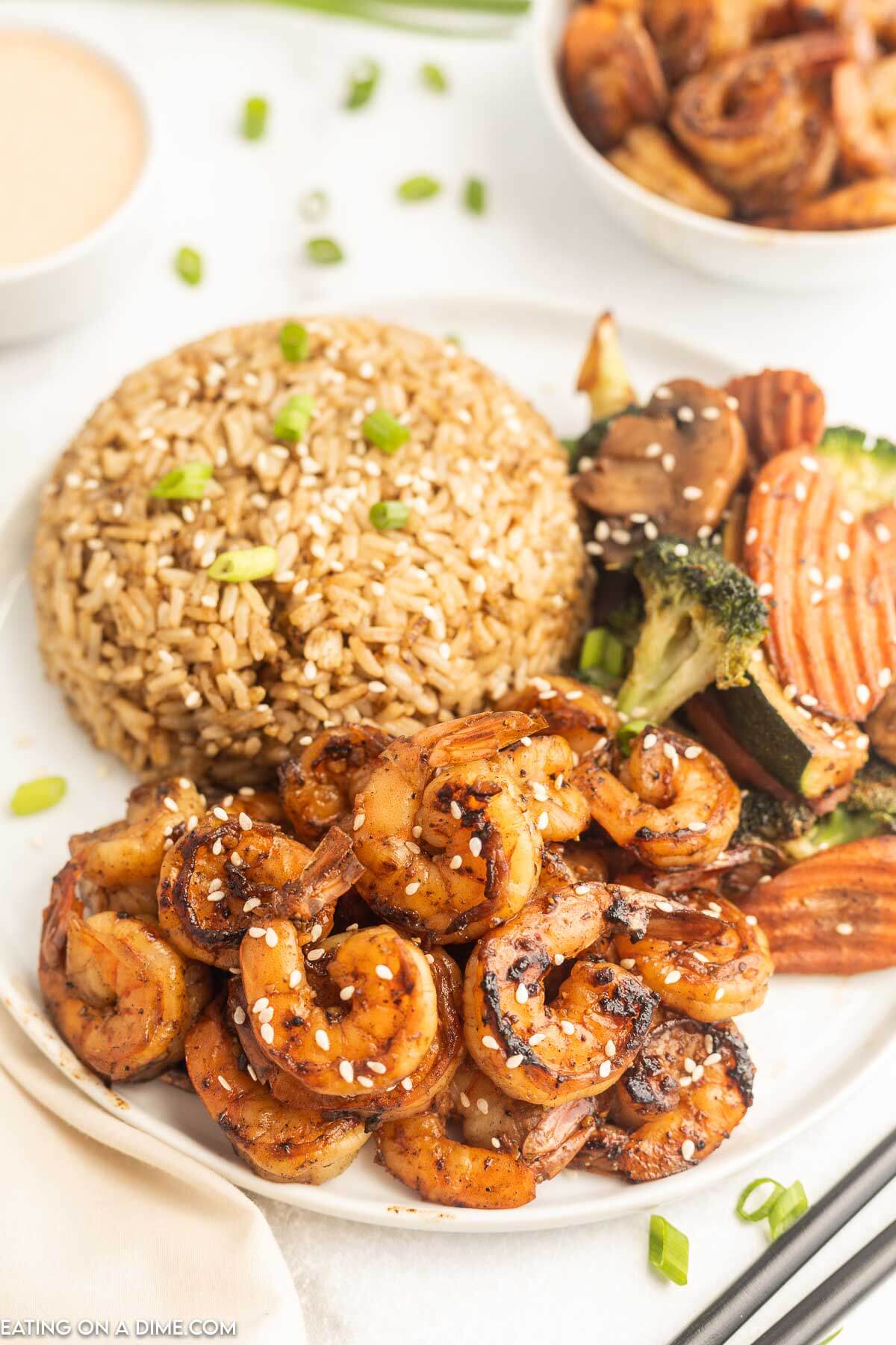 Hibachi shrimp on a plate with a side of fried rice and roasted veggies on a plate