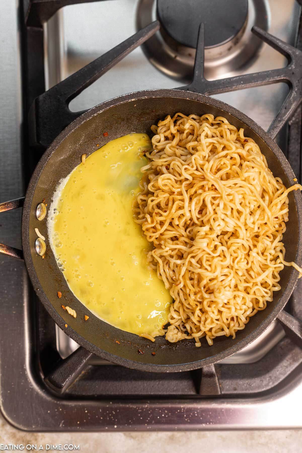 cooking the eggs in the skillet with the noodles