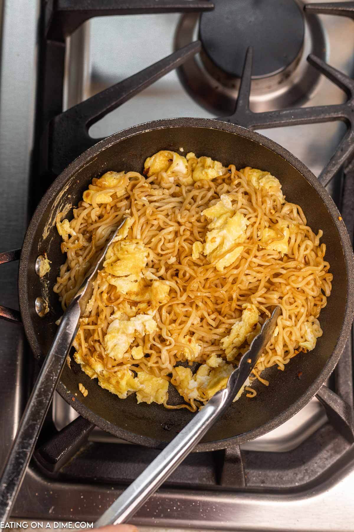 Tossing the noodles together with the scrambled eggs in a skillet