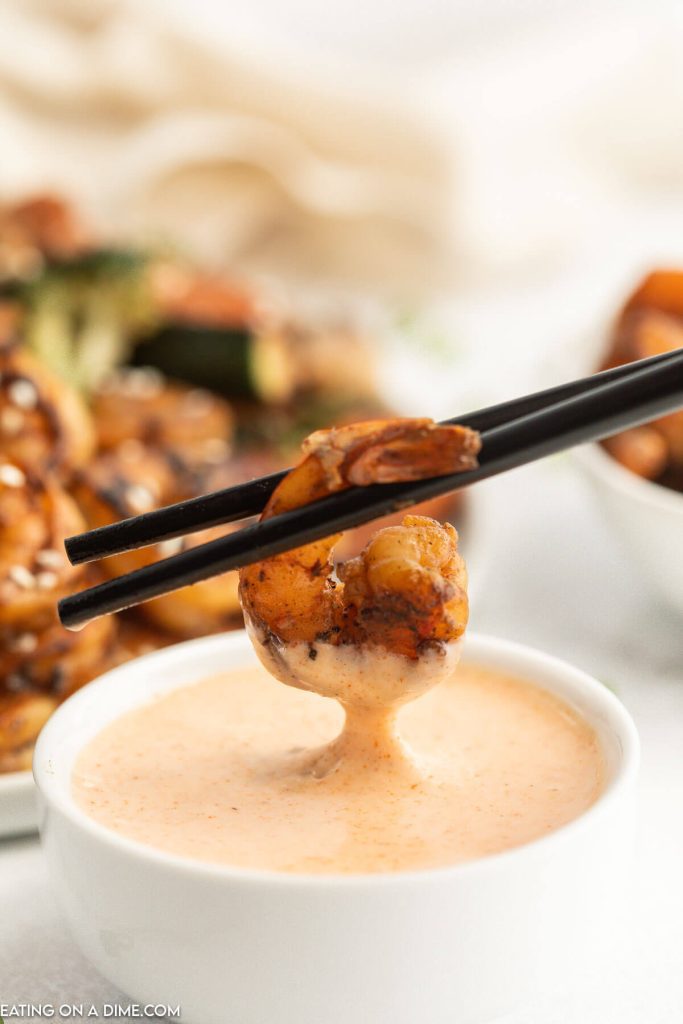 Close up image of dipping shrimp in a bowl of yum yum sauce