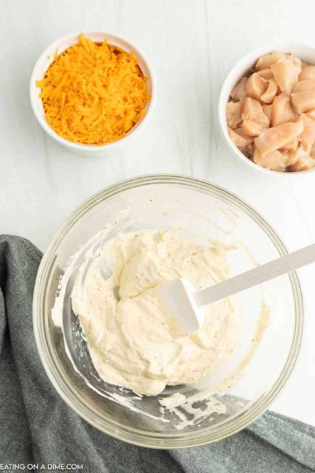Mixing the cream based ingredients in a clear bowl with a spatula.