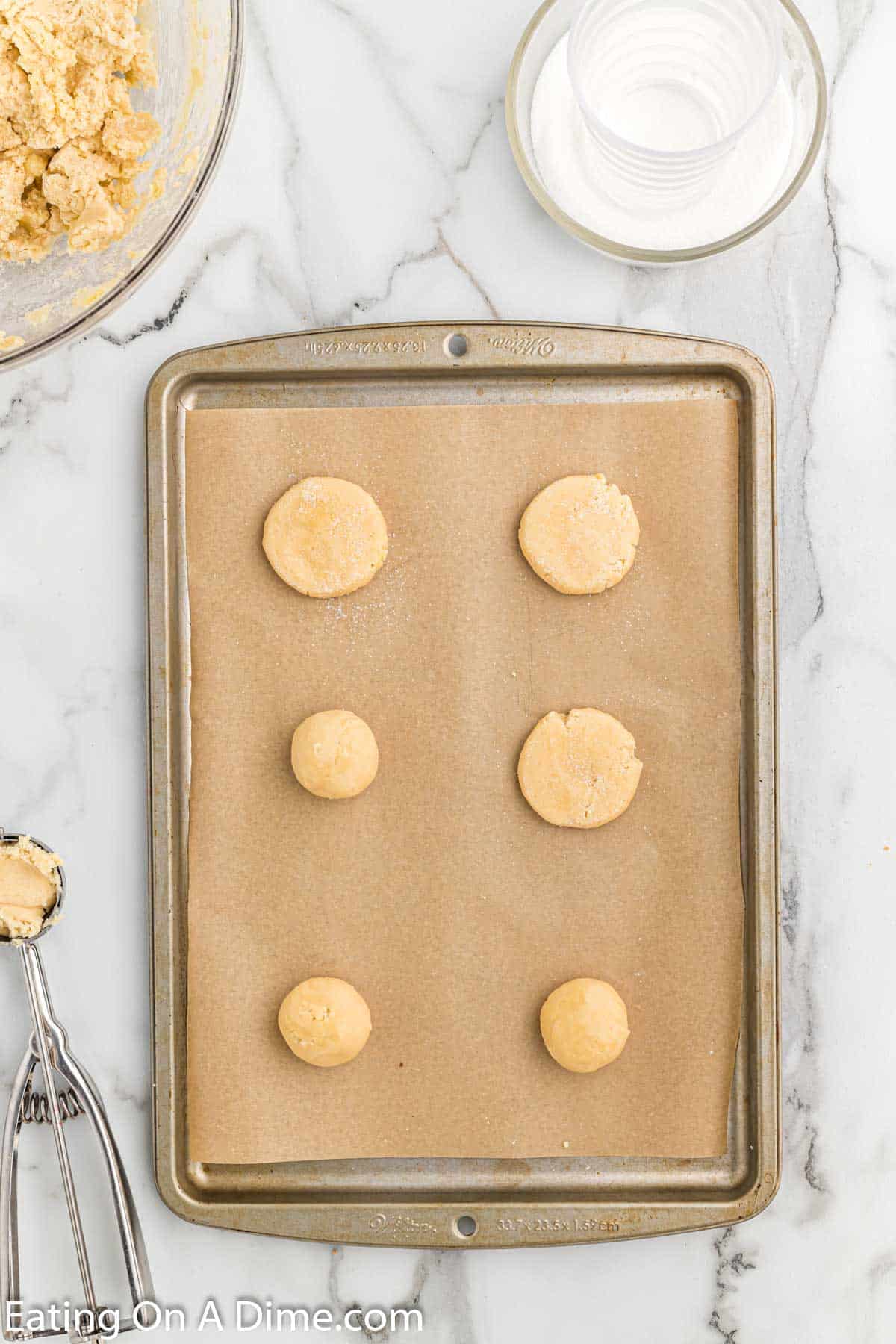 Dropping the sugar cookie dough balls onto baking sheet lined with parchment paper