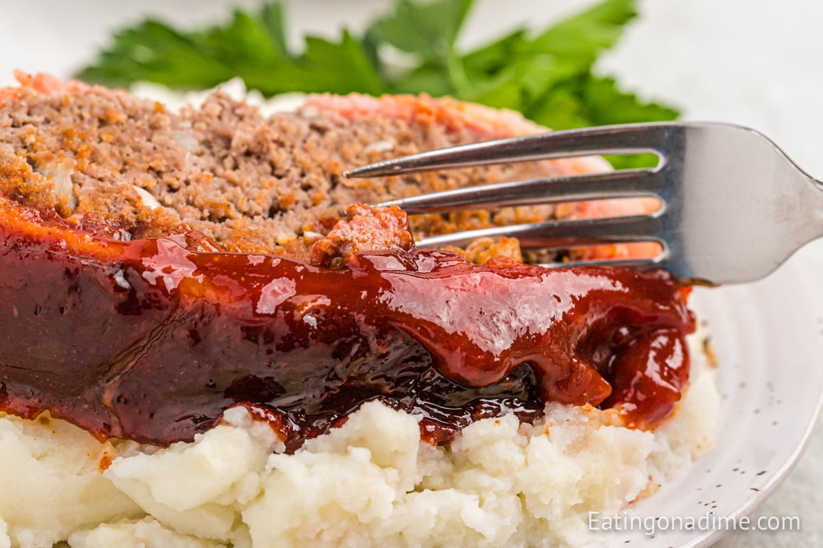 A slice of bacon wrapped meatloaf on a plate with a fork.