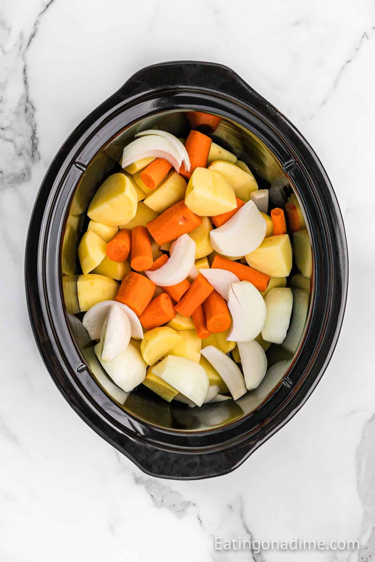 Chopped carrots, potatoes, and onions in the slow cooker.