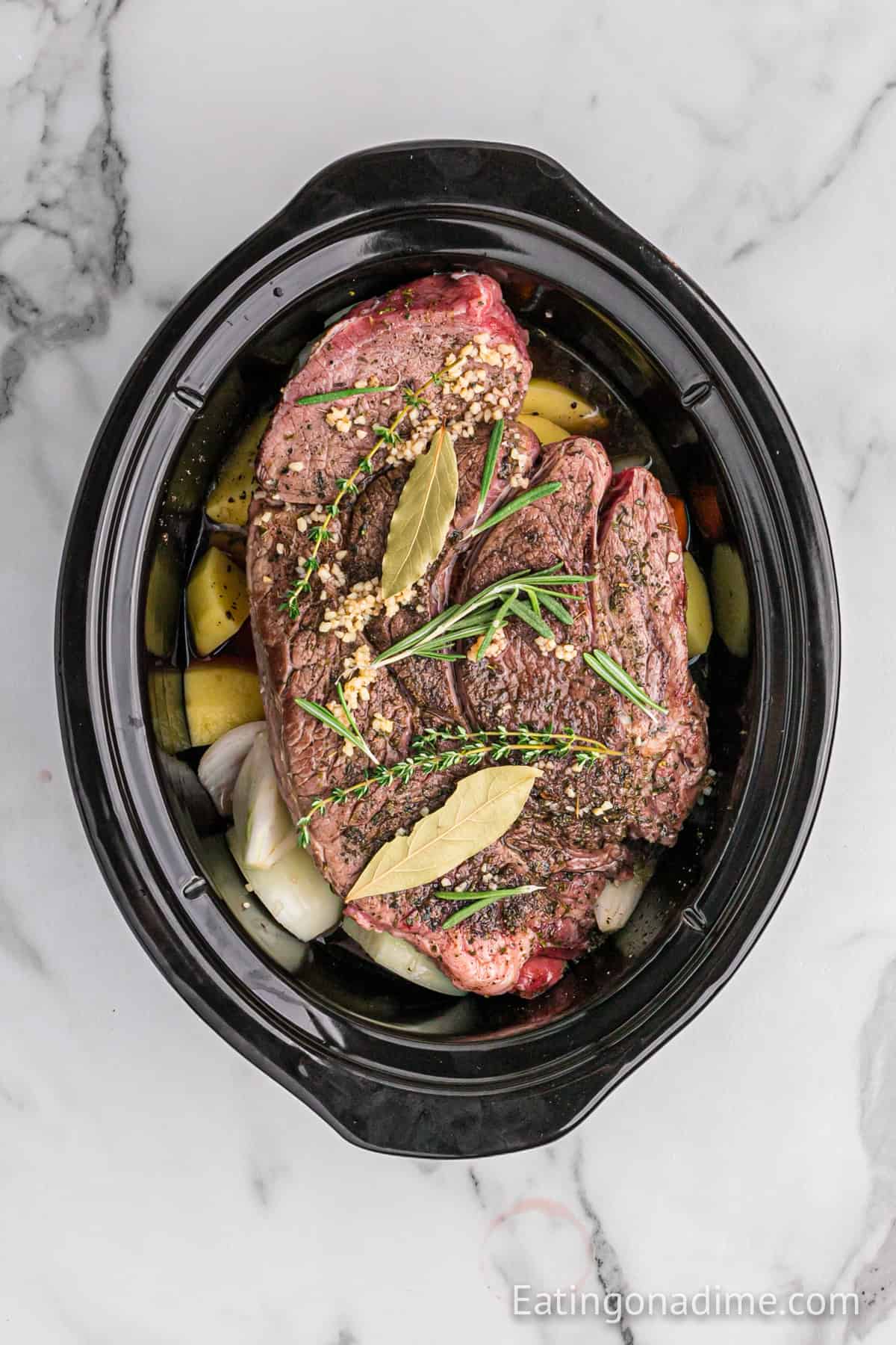 Seasoned seared roast placed on top of the vegetables in the slow cooker.