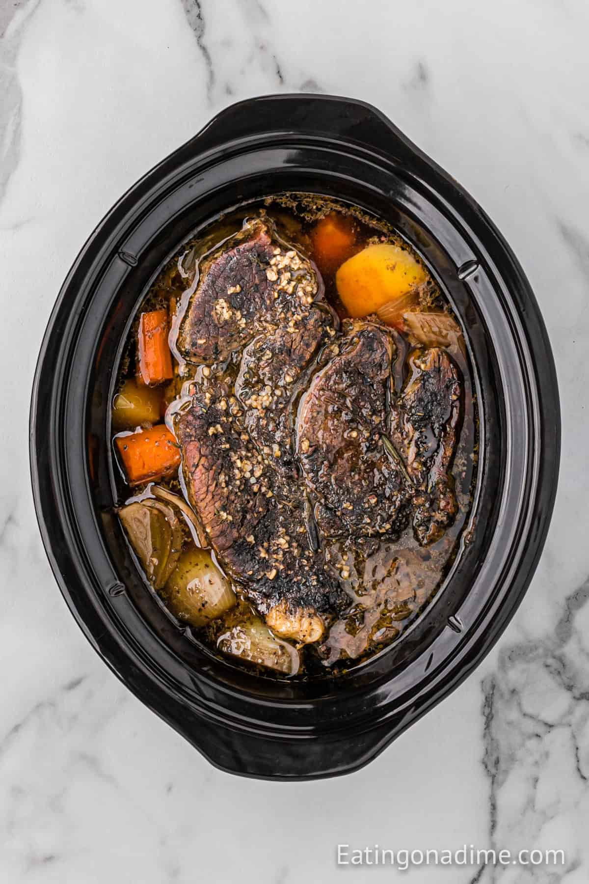 Cooked roast in the slow cooker with carrots, potatoes and onions.
