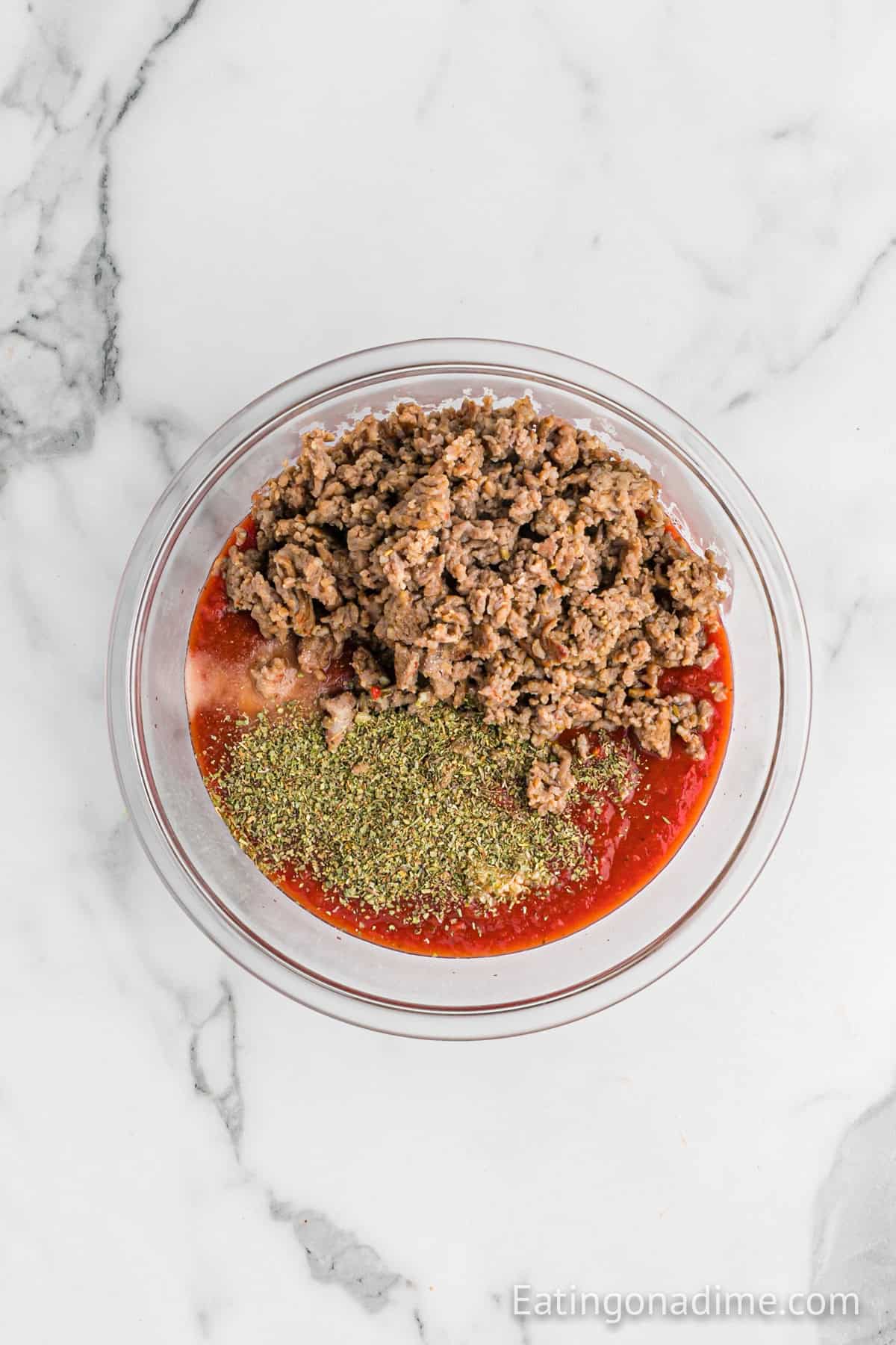 Cooked sausage mixed with tomatoes and spices in a bowl.
