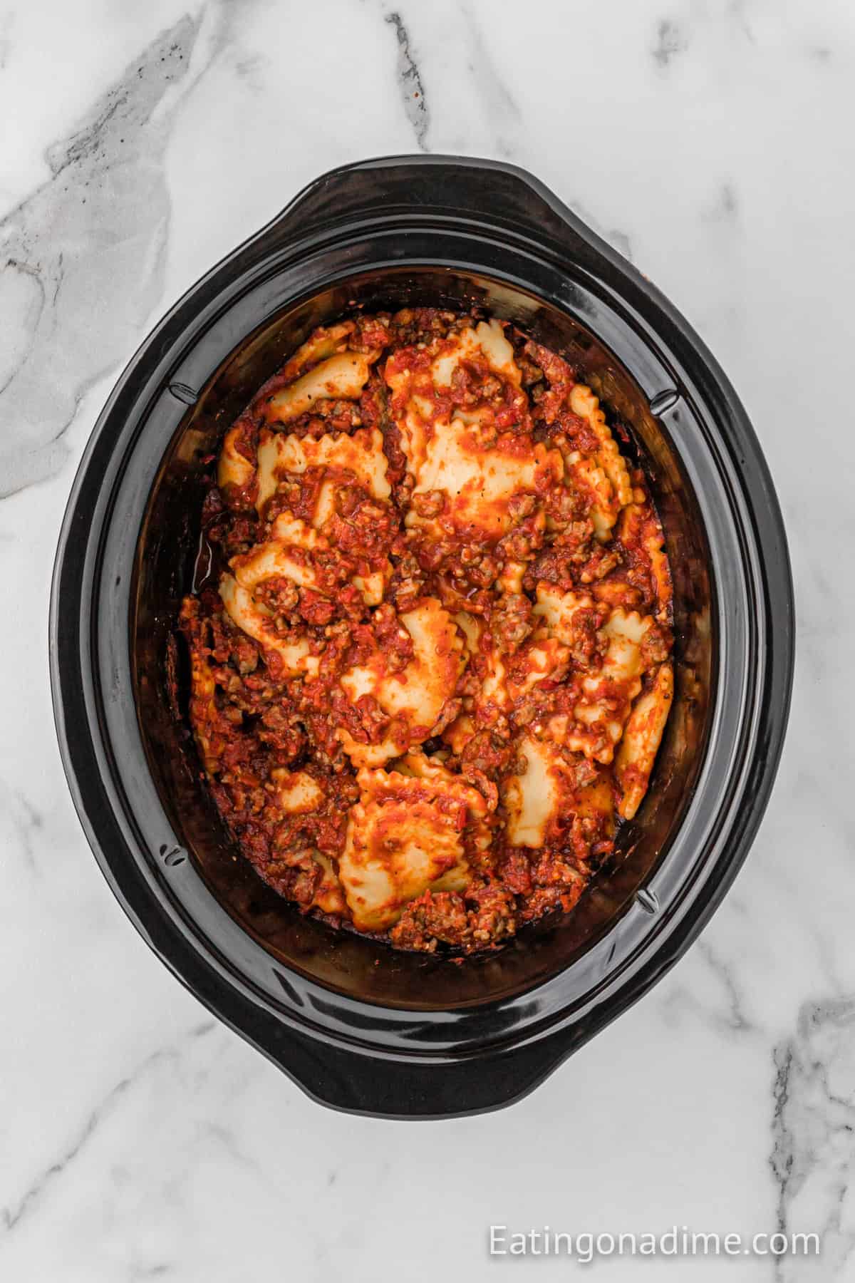 Ravioli and sausage mixture poured into a crockpot.